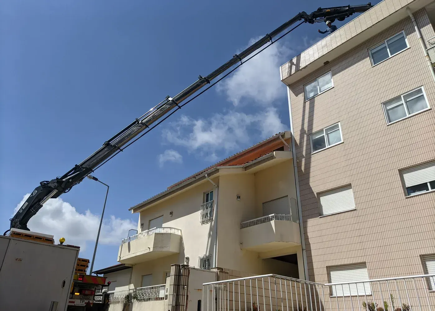 Trabalhos em cobertura acompanhados com recurso a grua em edifício habitacional